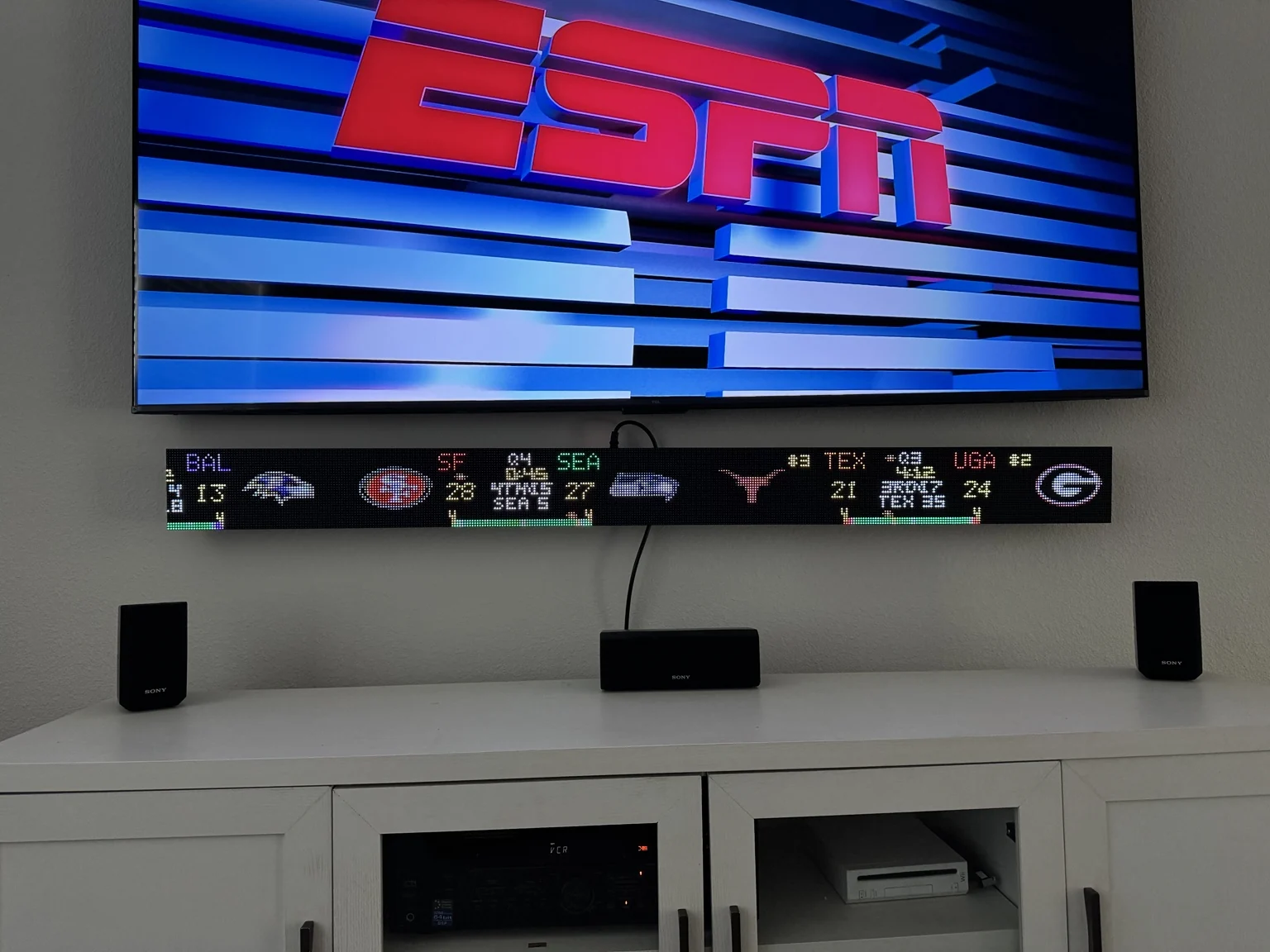 GameLine Pro showing football scores below a wall-mounted TV